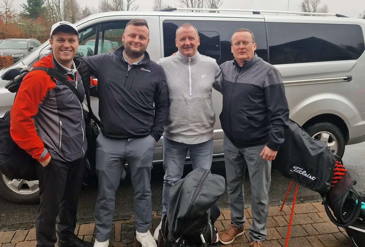 Four golfers and their golf bags beside the minibus