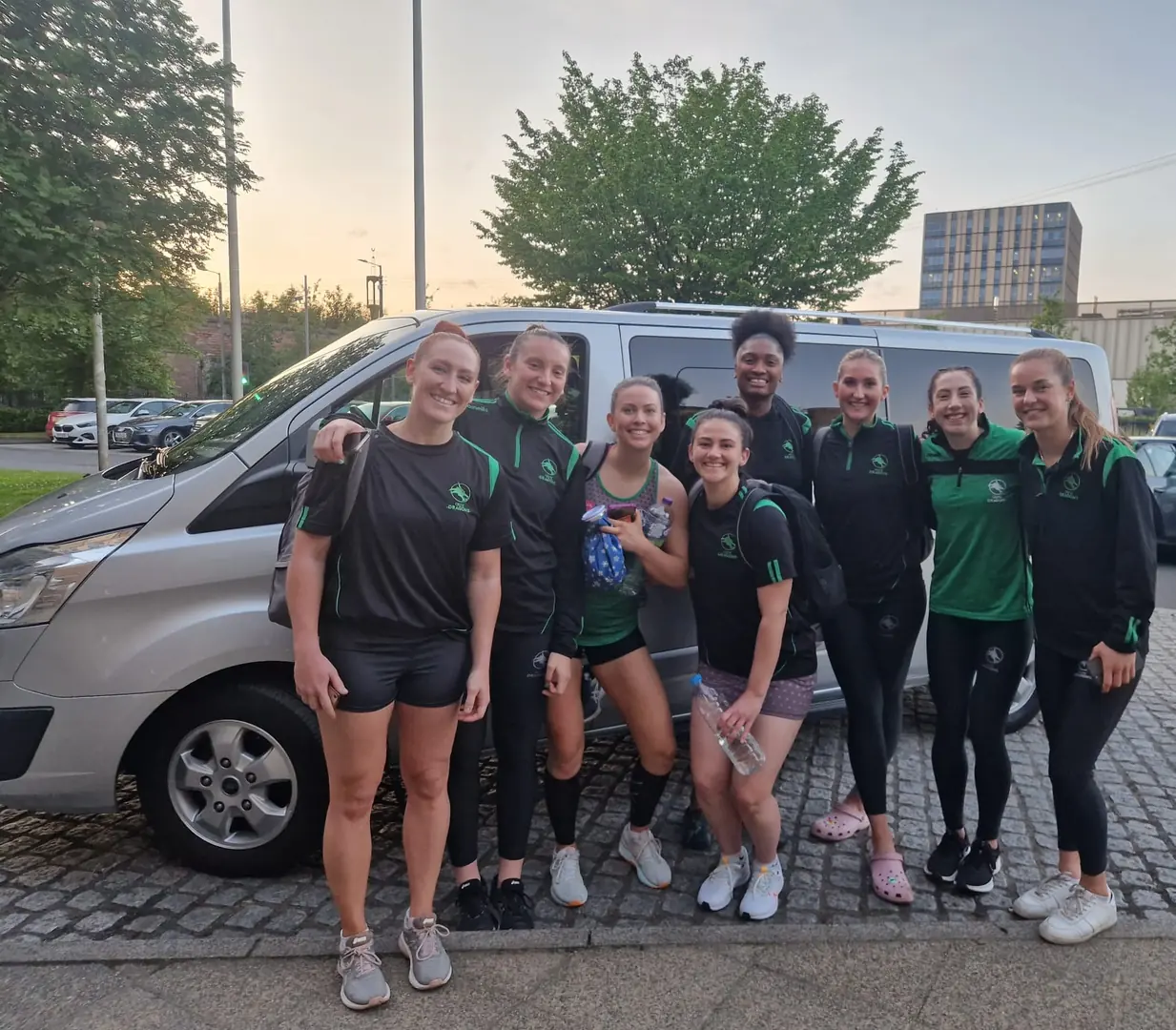 A group in sports clothing beside the B-Direct minibus